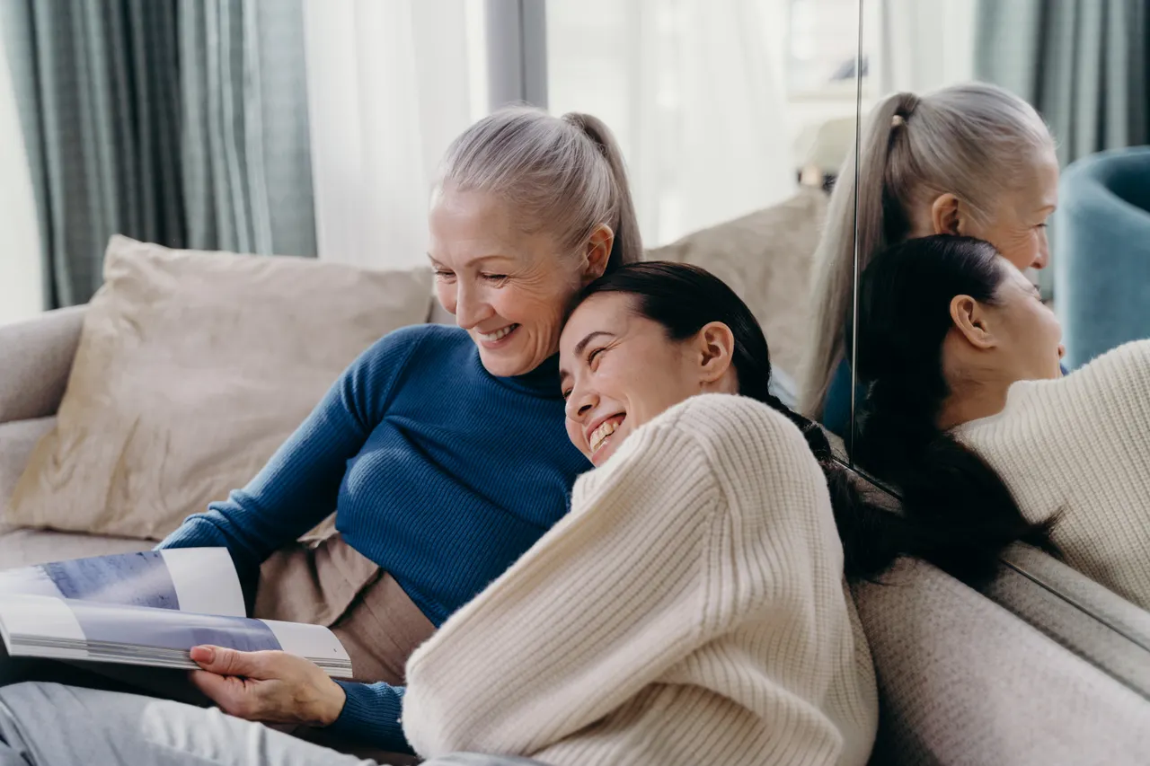 An older woman and a younger family member enjoying time together on a sofa.