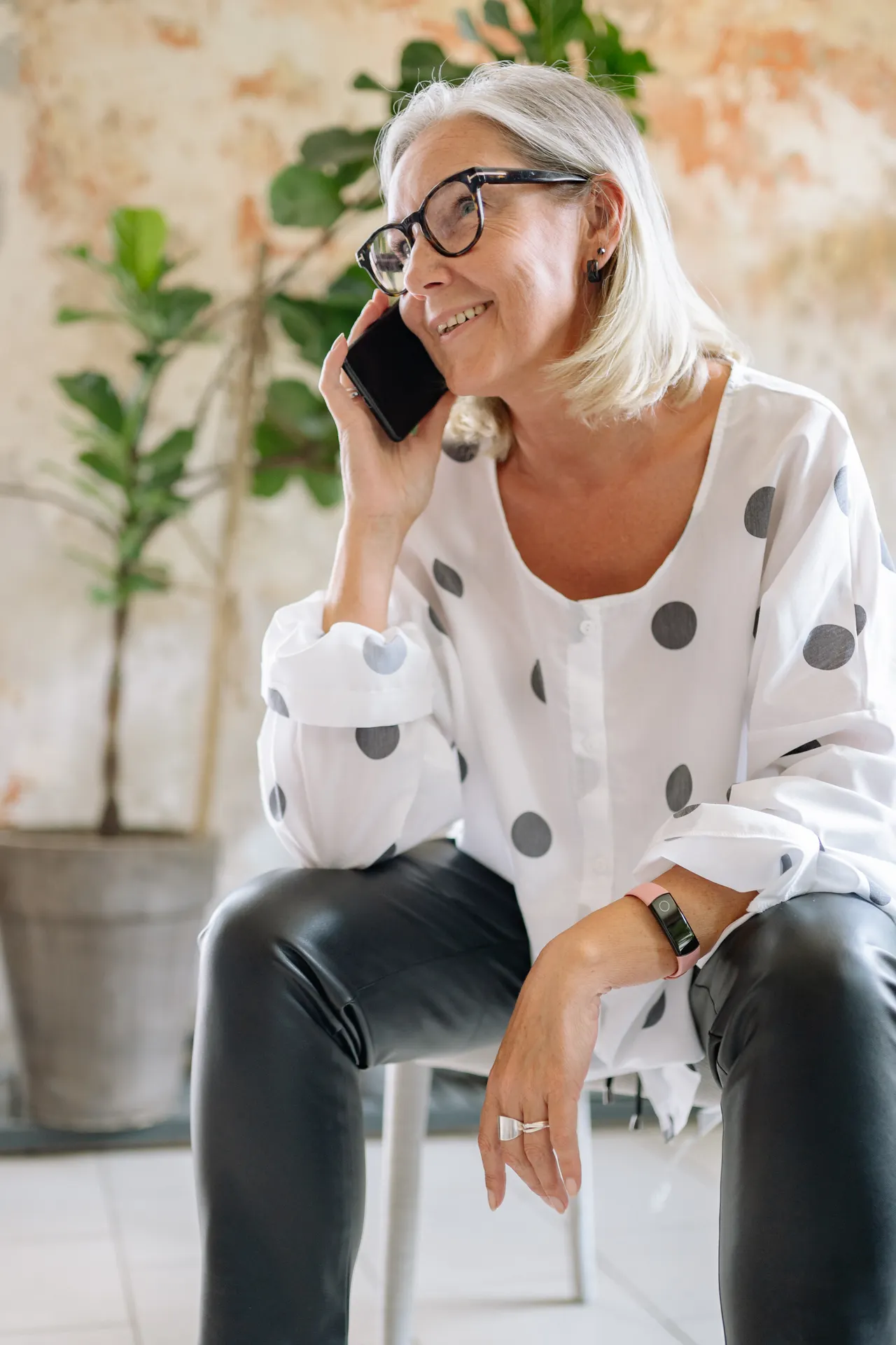 An older woman smiling while talking on her phone at home.